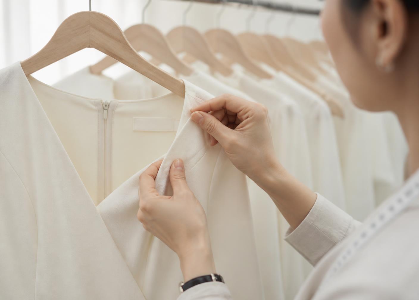Quality inspector checking the seam of a finished ivory dress